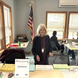 photo of long-standing volunteer standing at greeter table