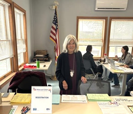 photo of long-standing volunteer standing at greeter table